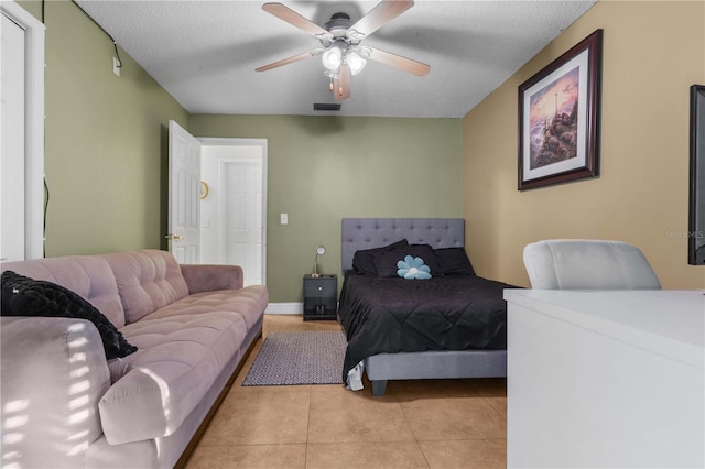 tiled bedroom featuring ceiling fan and a textured ceiling