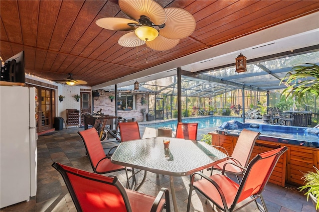 view of patio / terrace with a pool with hot tub, ceiling fan, and glass enclosure