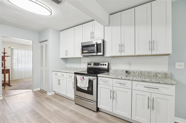 kitchen featuring white cabinetry, stainless steel appliances, a textured ceiling, and light wood-type flooring