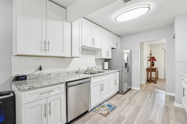 kitchen with sink, white cabinetry, stainless steel appliances, a textured ceiling, and decorative backsplash