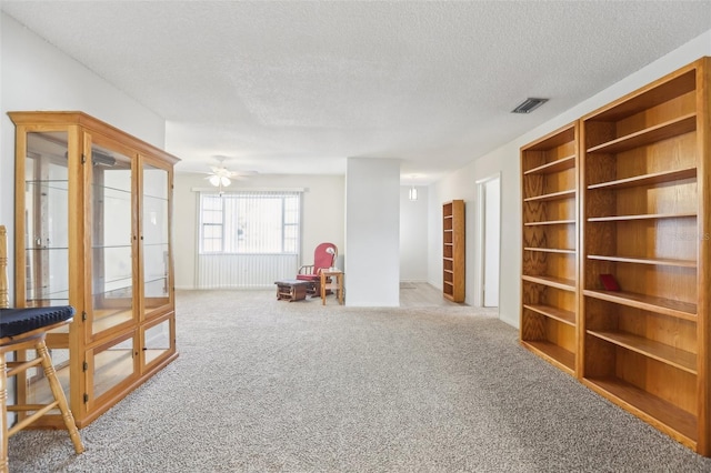 playroom with ceiling fan, light colored carpet, built in features, and a textured ceiling