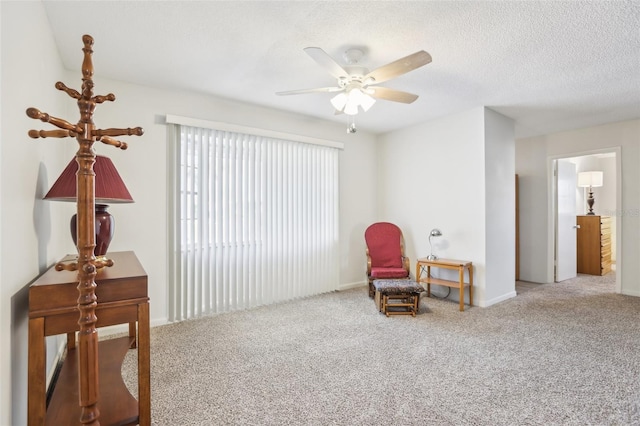 living area featuring ceiling fan, carpet floors, and a textured ceiling