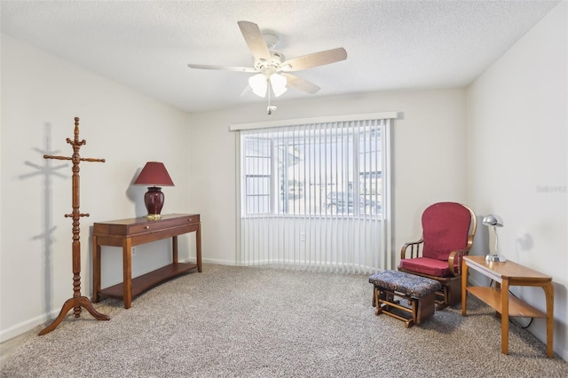 sitting room with ceiling fan, carpet floors, and a textured ceiling