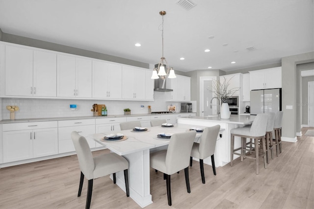 kitchen featuring an island with sink, white cabinets, and decorative light fixtures