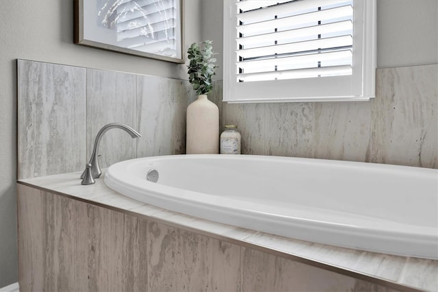 bathroom featuring a healthy amount of sunlight and tiled bath