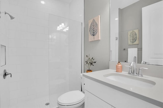 bathroom with vanity, a tile shower, and toilet