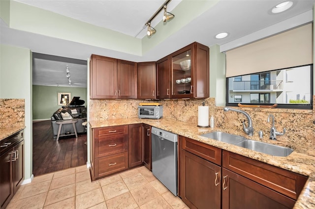 kitchen featuring dishwasher, sink, light tile patterned floors, light stone counters, and track lighting