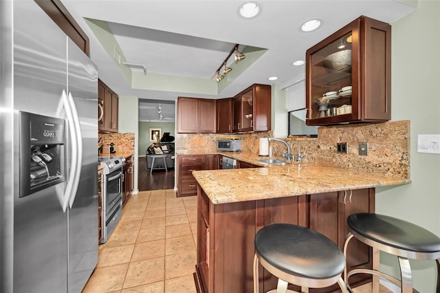 kitchen with sink, appliances with stainless steel finishes, a kitchen breakfast bar, track lighting, and kitchen peninsula