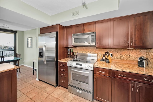 kitchen with light stone countertops, light tile patterned flooring, appliances with stainless steel finishes, and backsplash