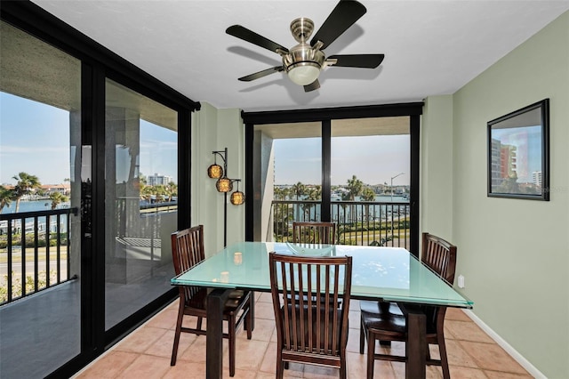 dining space with expansive windows, a water view, and light tile patterned floors