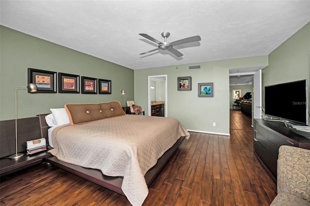 bedroom with connected bathroom, dark wood-type flooring, and ceiling fan