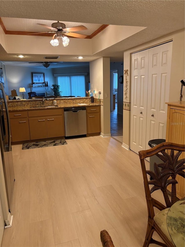 kitchen with appliances with stainless steel finishes, sink, dark stone countertops, light hardwood / wood-style floors, and a textured ceiling