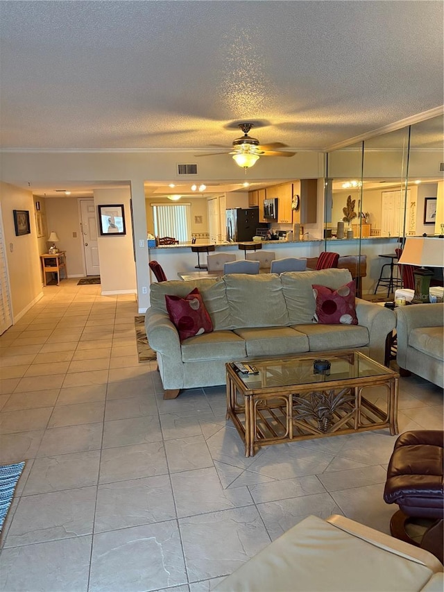 living room with ceiling fan, ornamental molding, and a textured ceiling