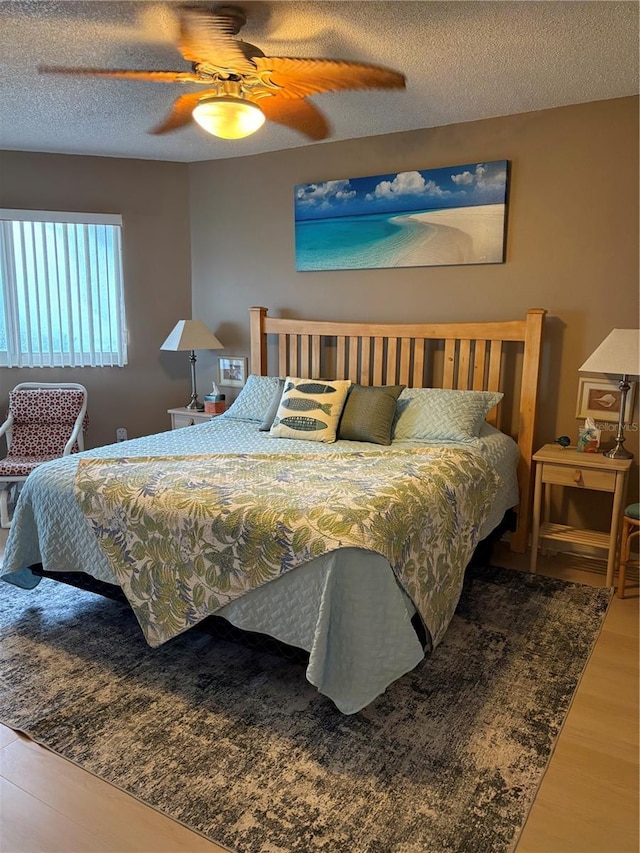 bedroom featuring ceiling fan, wood-type flooring, and a textured ceiling