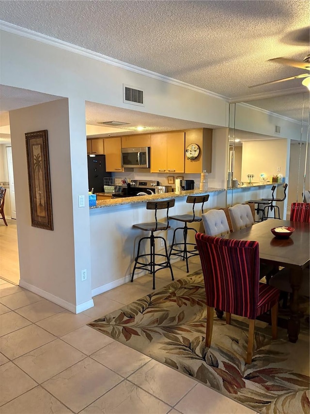 dining space with ceiling fan, ornamental molding, and a textured ceiling