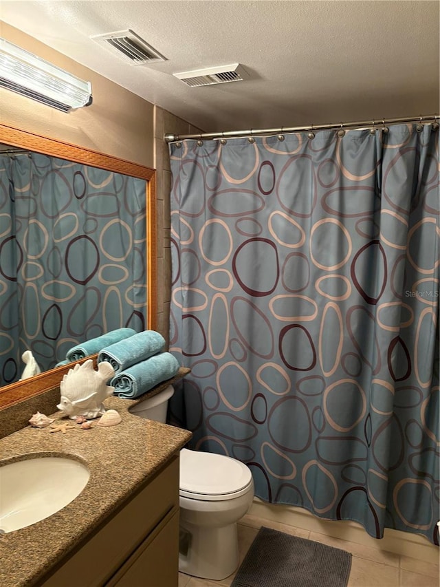 bathroom with tile patterned floors, toilet, a textured ceiling, and vanity