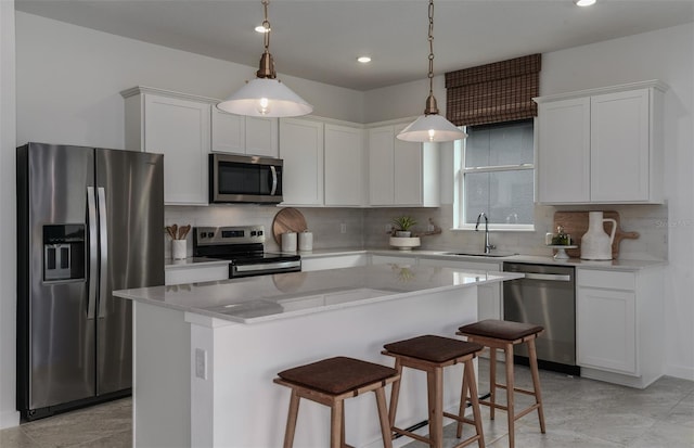 kitchen with white cabinetry, tasteful backsplash, decorative light fixtures, a center island, and appliances with stainless steel finishes