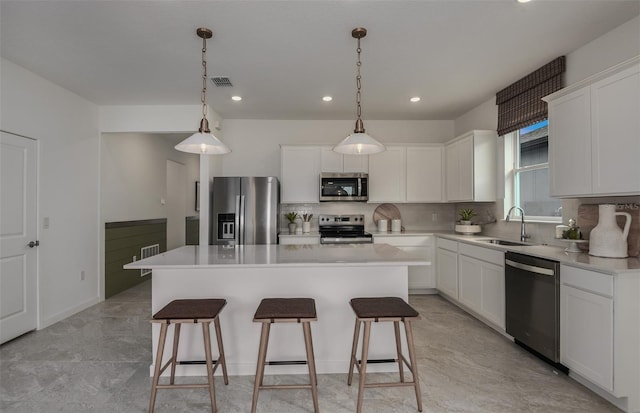 kitchen featuring sink, appliances with stainless steel finishes, hanging light fixtures, a center island, and white cabinets