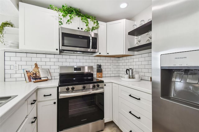 kitchen featuring stainless steel appliances, white cabinets, and backsplash