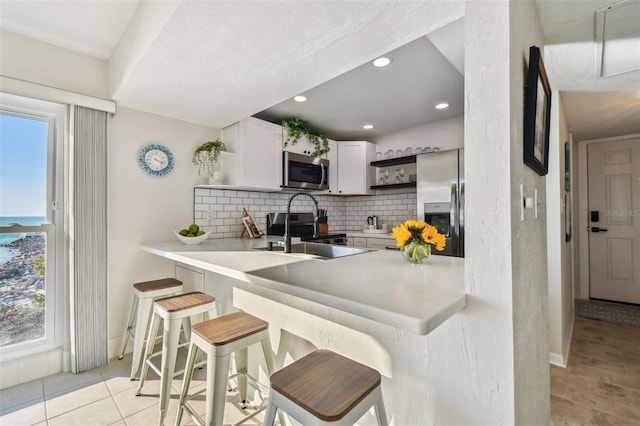 kitchen with white cabinetry, stainless steel appliances, kitchen peninsula, and a breakfast bar area