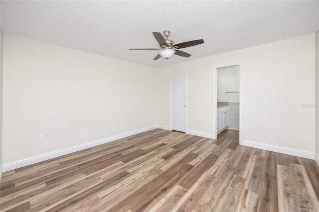 unfurnished bedroom featuring connected bathroom, a textured ceiling, light hardwood / wood-style floors, and ceiling fan