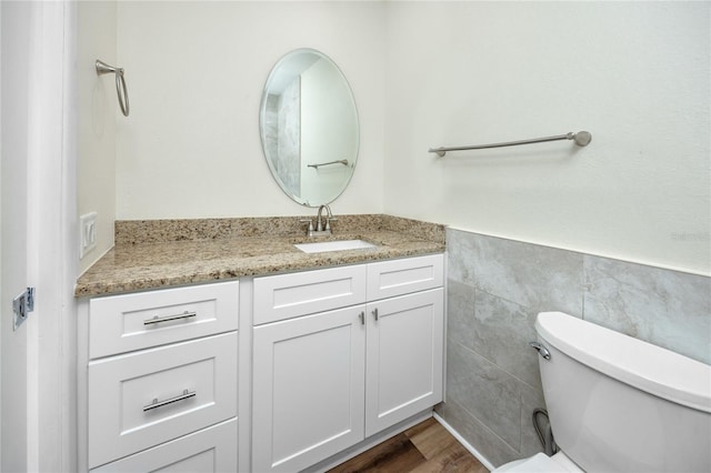 bathroom featuring hardwood / wood-style flooring, vanity, tile walls, and toilet