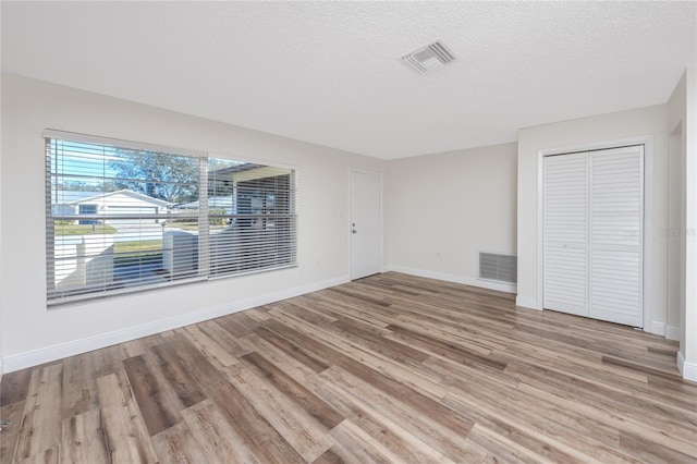 unfurnished bedroom featuring a closet, a textured ceiling, and light hardwood / wood-style flooring