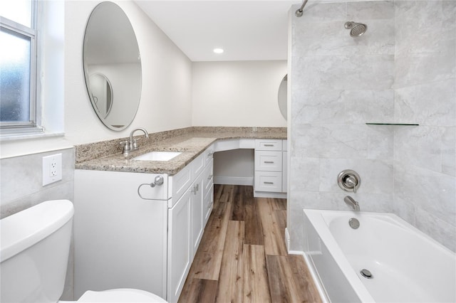 full bathroom featuring tiled shower / bath combo, vanity, hardwood / wood-style floors, and toilet