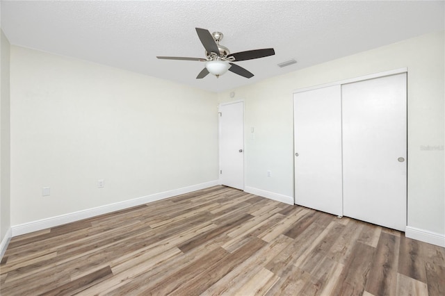 unfurnished bedroom featuring ceiling fan, light hardwood / wood-style flooring, a closet, and a textured ceiling