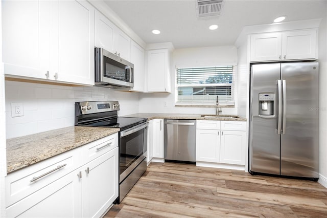 kitchen with white cabinetry, sink, stainless steel appliances, and light hardwood / wood-style floors