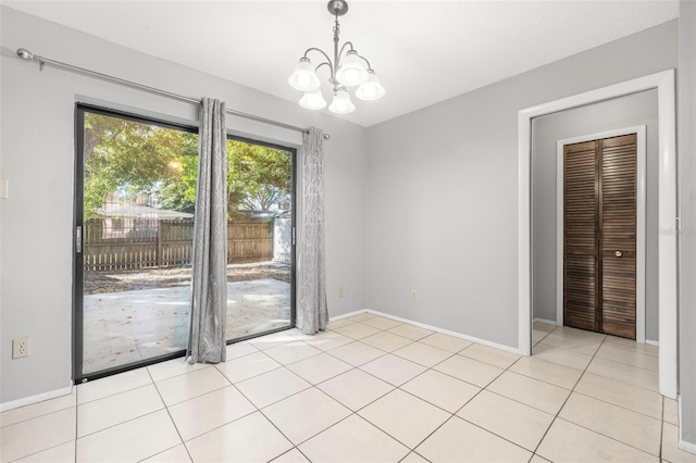 tiled spare room with an inviting chandelier