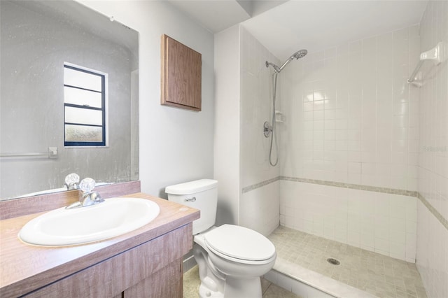 bathroom with vanity, toilet, and tiled shower