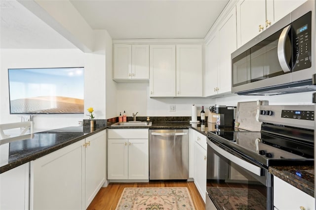 kitchen with white cabinetry, appliances with stainless steel finishes, sink, and dark stone countertops