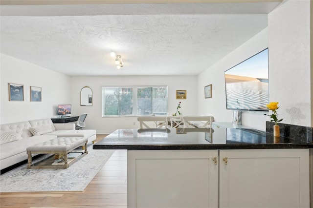 kitchen with white cabinetry, light hardwood / wood-style flooring, and a textured ceiling