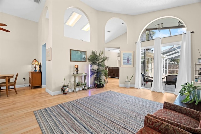 living room with a towering ceiling, light hardwood / wood-style floors, and ceiling fan