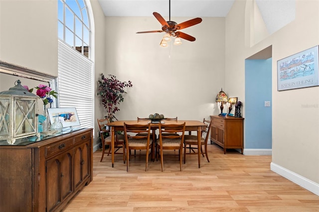 dining area featuring ceiling fan, a towering ceiling, and light wood-type flooring