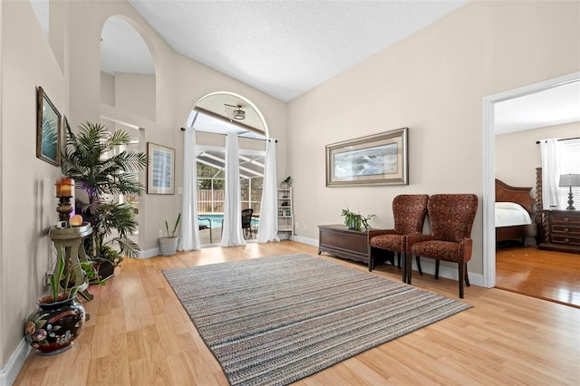 living area with lofted ceiling, light hardwood / wood-style floors, and a textured ceiling