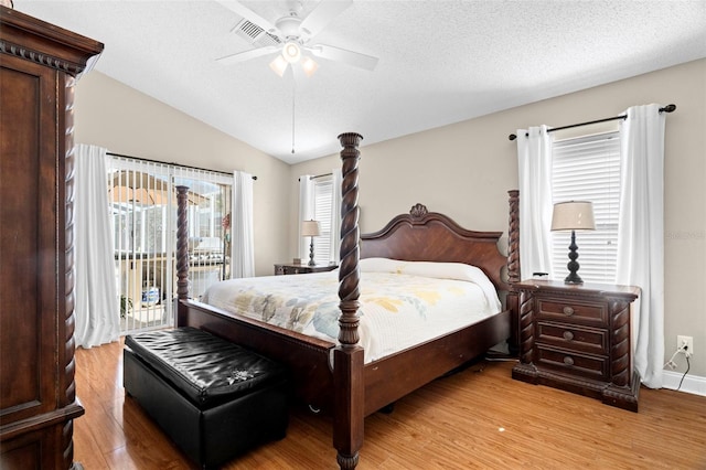 bedroom with ceiling fan, vaulted ceiling, a textured ceiling, access to outside, and light wood-type flooring