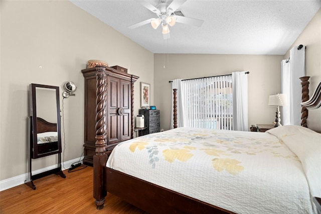 bedroom with ceiling fan, wood-type flooring, vaulted ceiling, and a textured ceiling