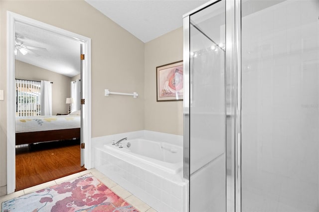 bathroom with lofted ceiling, tile patterned floors, shower with separate bathtub, and a textured ceiling