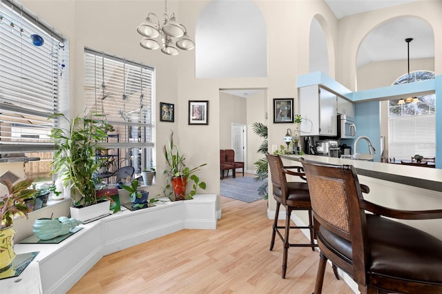 dining room featuring an inviting chandelier, high vaulted ceiling, and light hardwood / wood-style floors