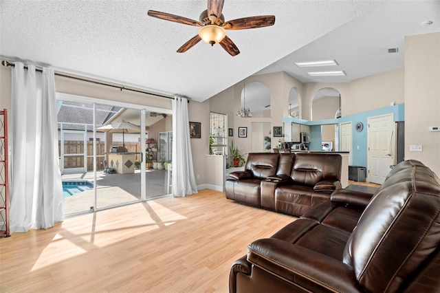 living room with lofted ceiling, ceiling fan, wood-type flooring, and a textured ceiling