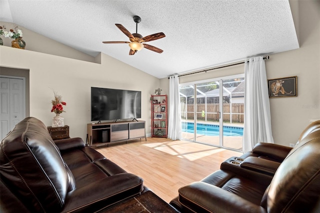 living room with hardwood / wood-style flooring, ceiling fan, lofted ceiling, and a textured ceiling