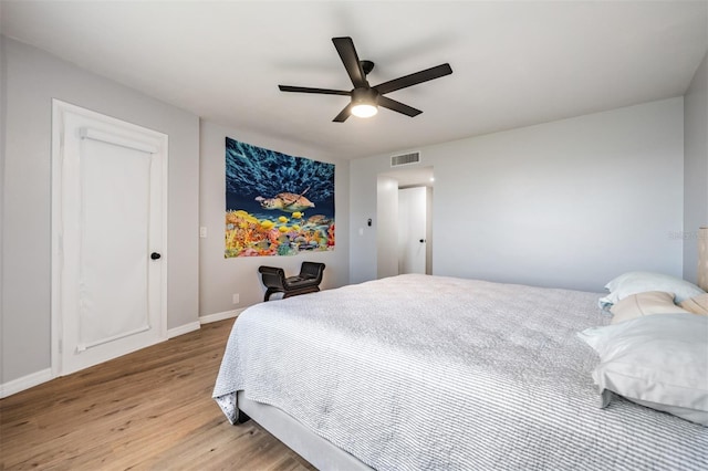 bedroom featuring light wood finished floors, a ceiling fan, visible vents, and baseboards