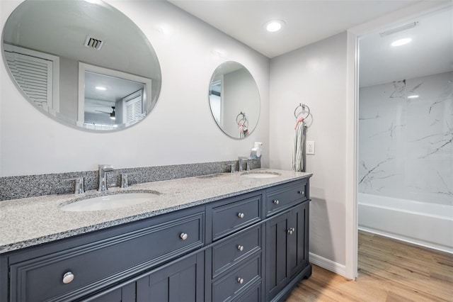 full bath featuring double vanity, wood finished floors, a sink, and visible vents