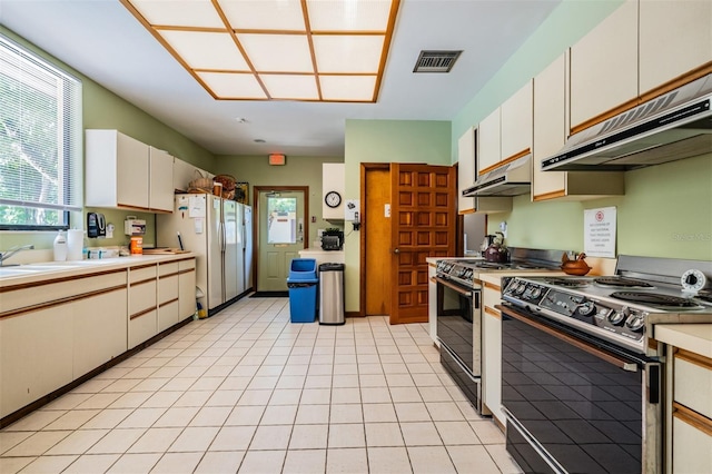 kitchen with black range with electric stovetop, electric range, a sink, visible vents, and freestanding refrigerator