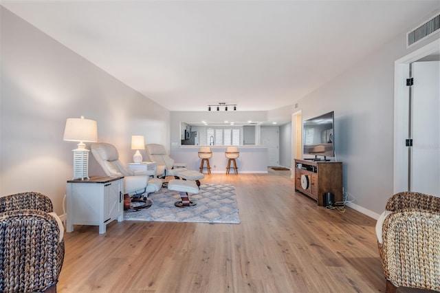 living area featuring baseboards, rail lighting, visible vents, and light wood-style floors