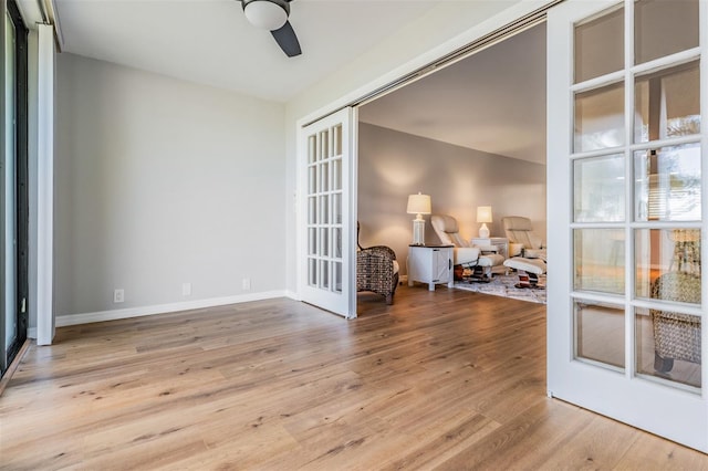 empty room with a ceiling fan, french doors, baseboards, and wood finished floors