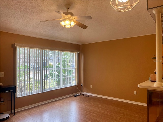 interior space with decorative columns, hardwood / wood-style floors, a textured ceiling, and ceiling fan