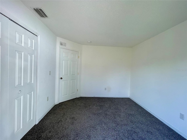 unfurnished bedroom featuring a textured ceiling and dark carpet